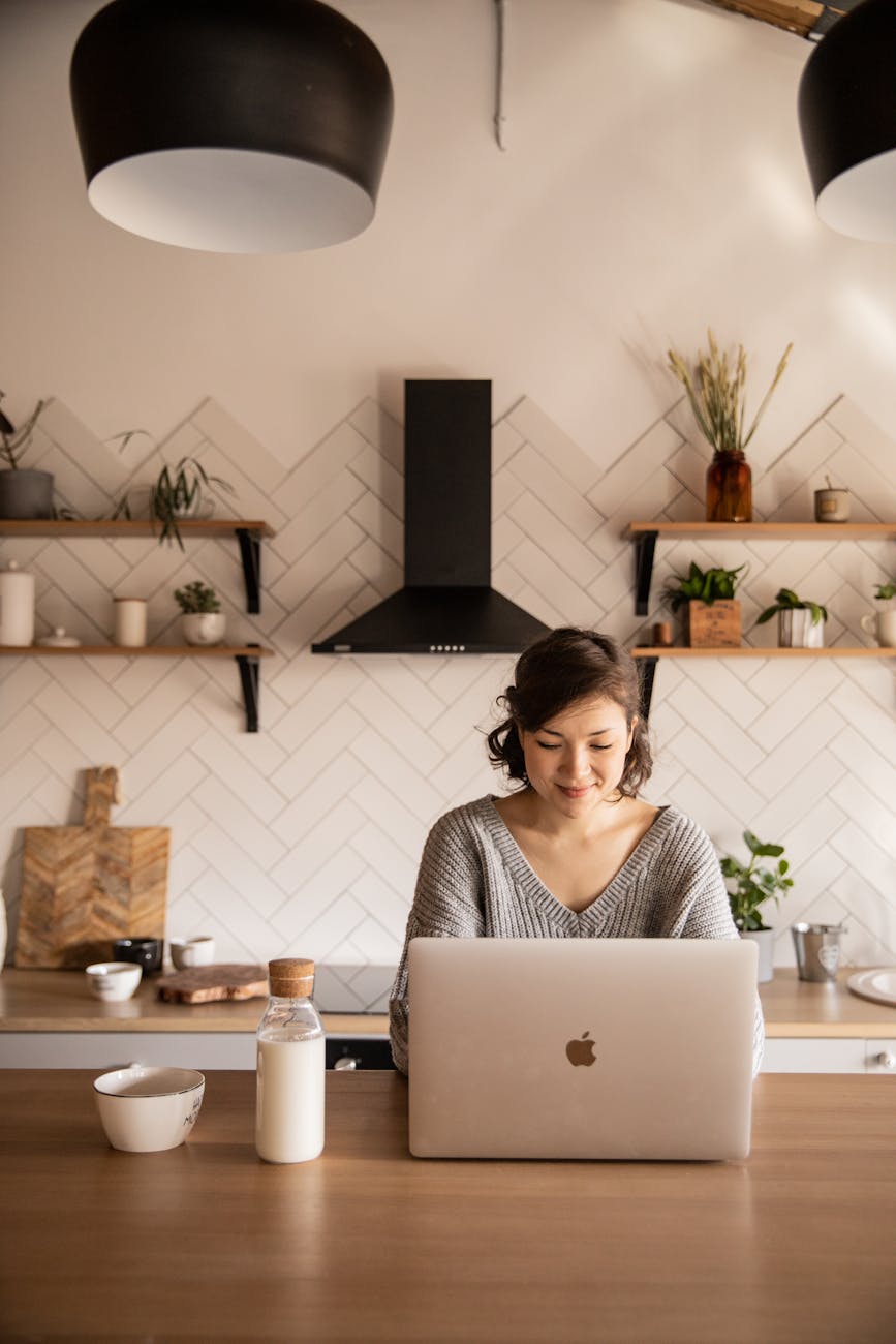 smiling woman using laptop in kitchen